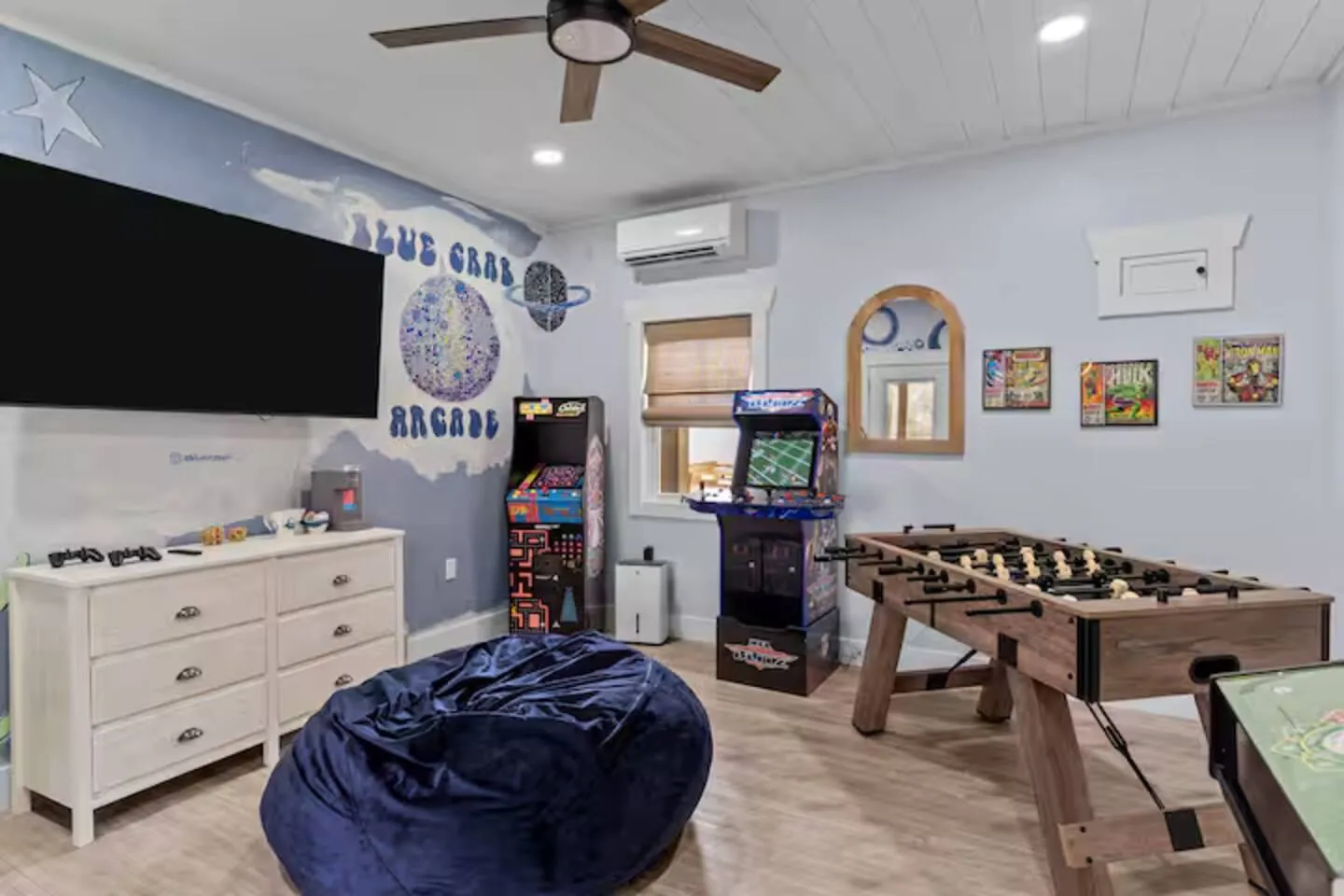 Arcade room with a foosball table, retro arcade cabinet, bean bag, and 65-inch TV
