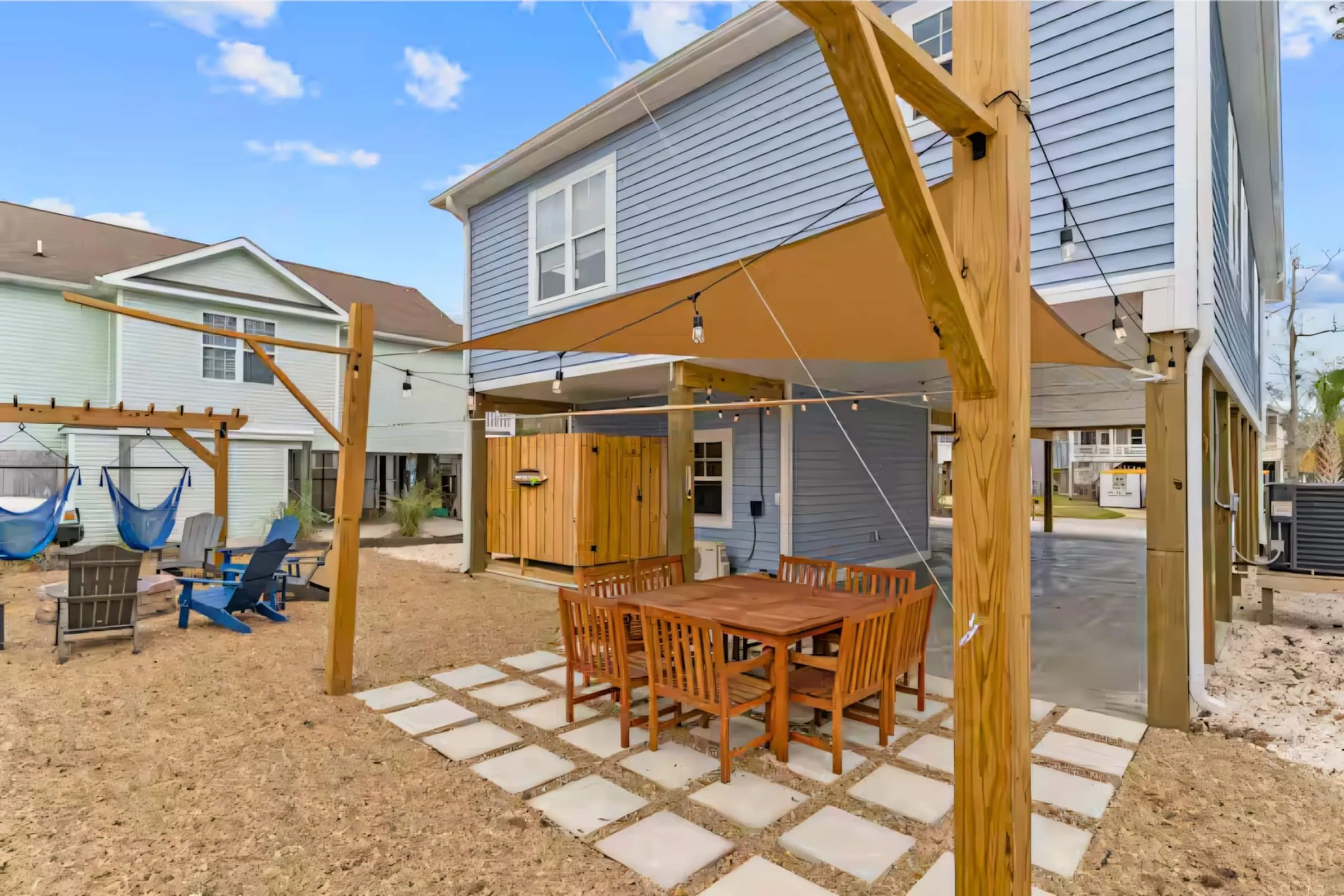 The fenced backyard: pergola dining, fire pit circle, and the back of the house