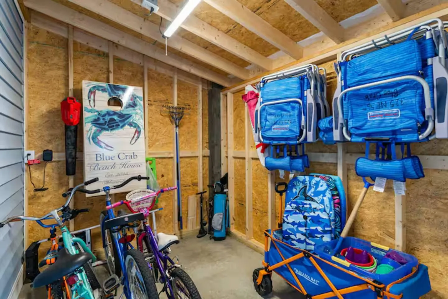 Garage with kids' and adult bikes, beach chairs, body boards, and a beach cart