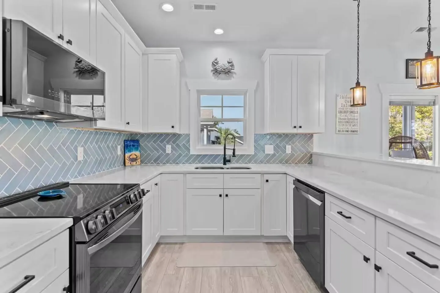 White shaker kitchen with sea-glass subway tile, gas range, and a window over the sink