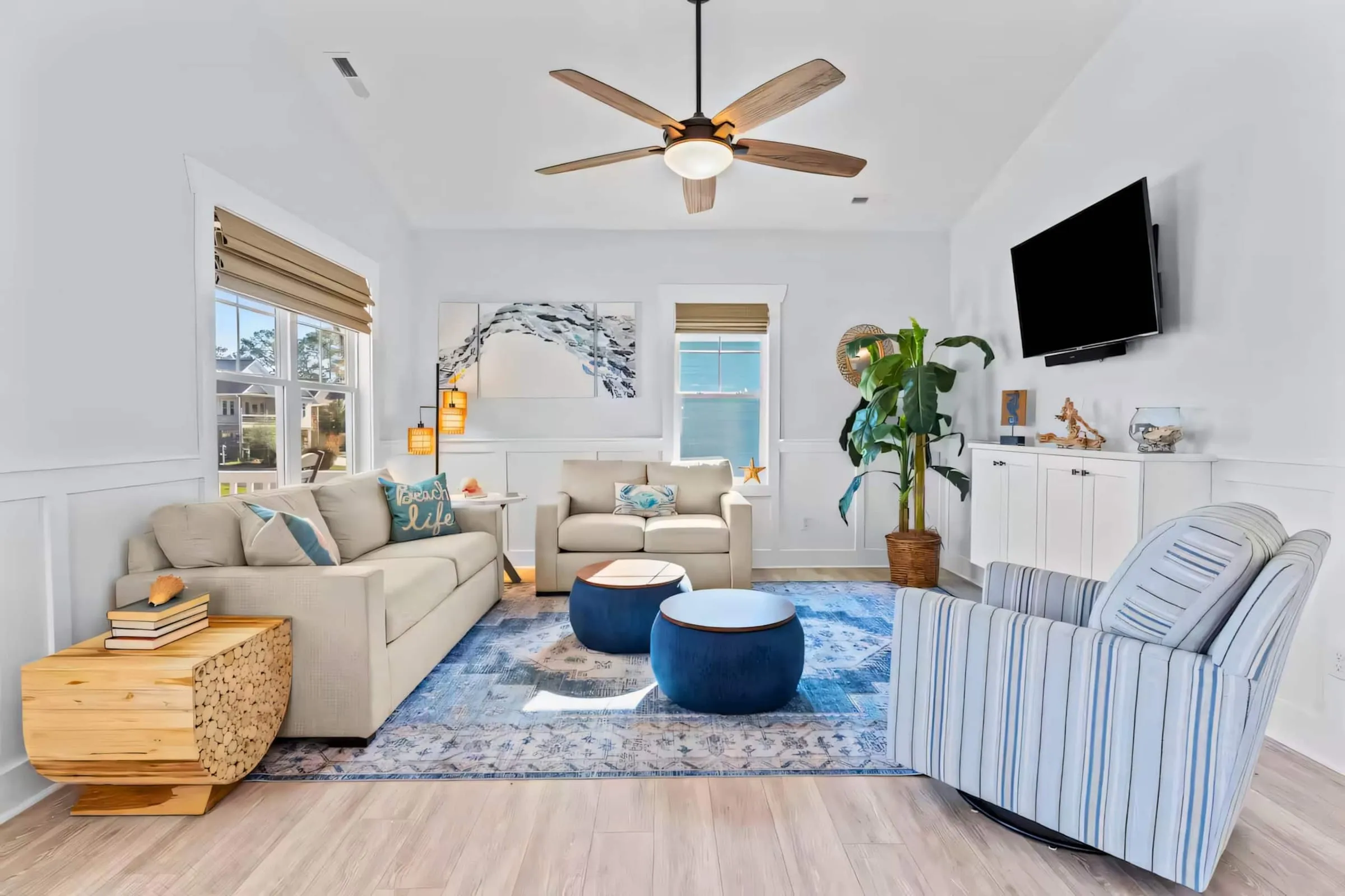 Bright living room with a sectional sofa, navy ottoman, coastal blue rug, and smart TV